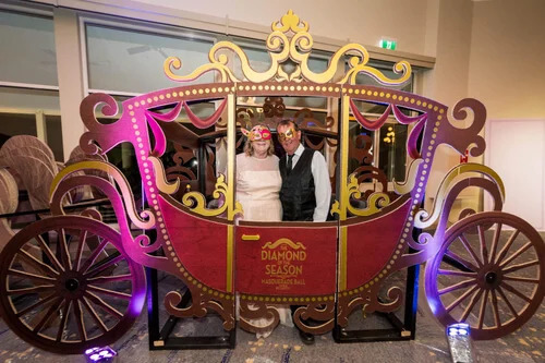 Guests posing inside a custom horse and carriage installation at the Clifford Craig Foundation masquerade gala. Bridgerton-Inspired Horse and Carriage Installation
