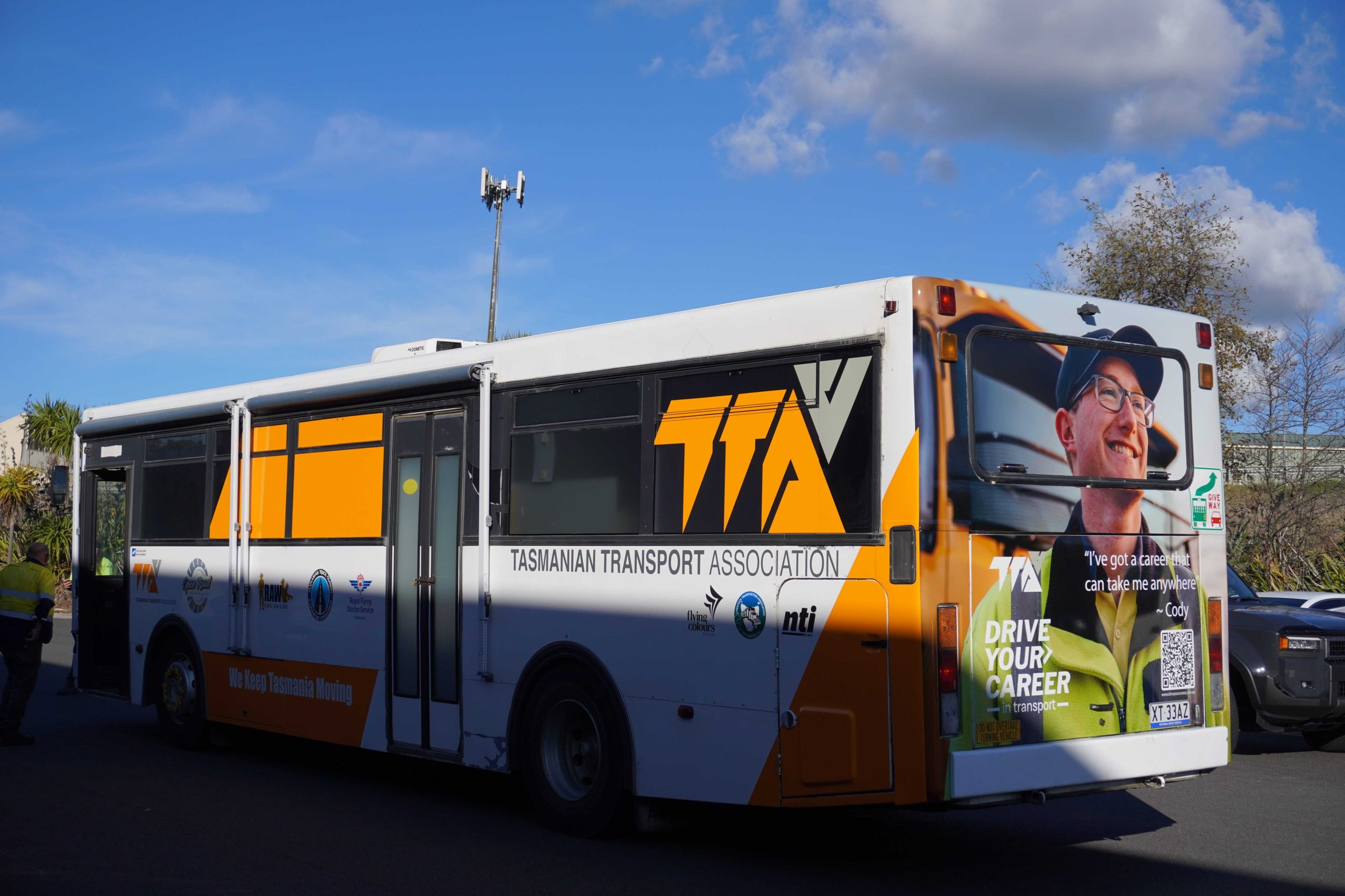Tasmanian Transport Association bus wrap installed by Flying Colours Group featuring bold orange and white branding.