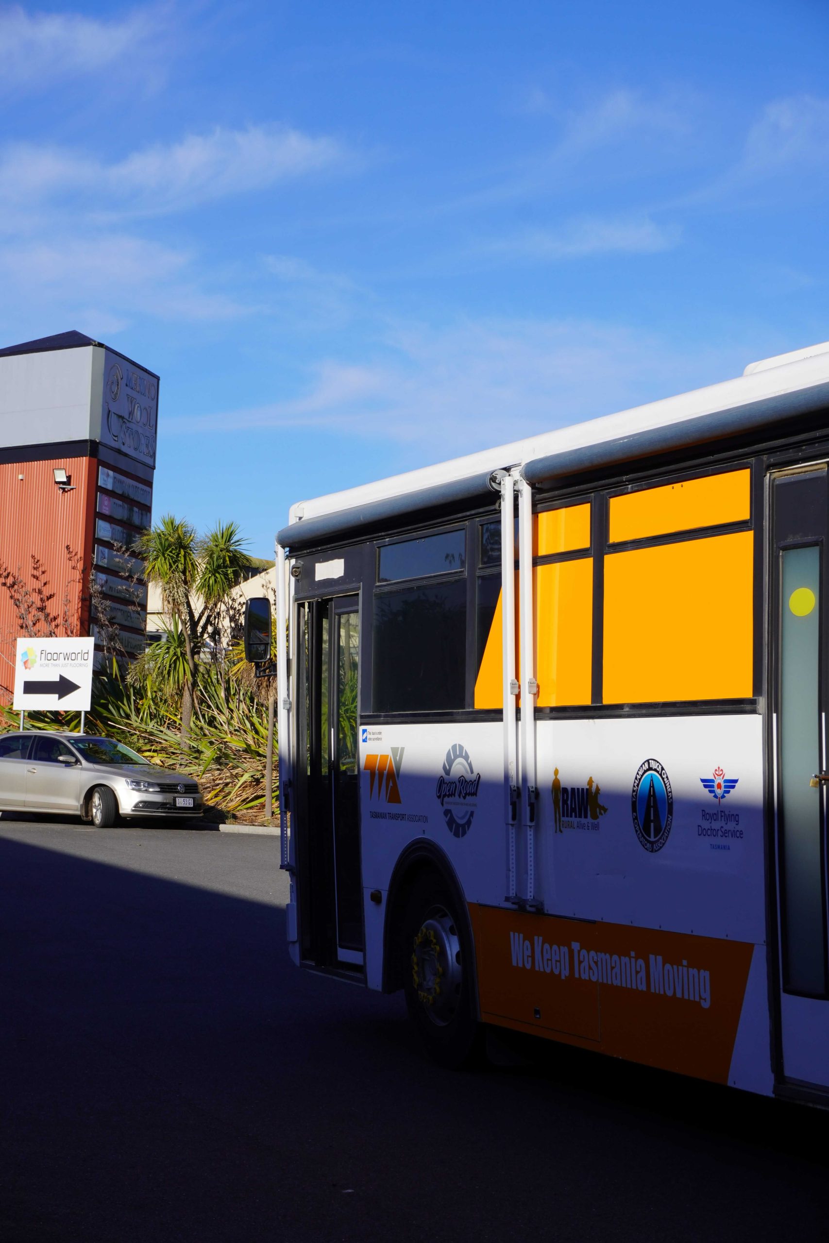 TTA Bus Wrap Side Profile Tasmanian Transport Association bus wrap installed by Flying Colours Group featuring bold orange and white branding.