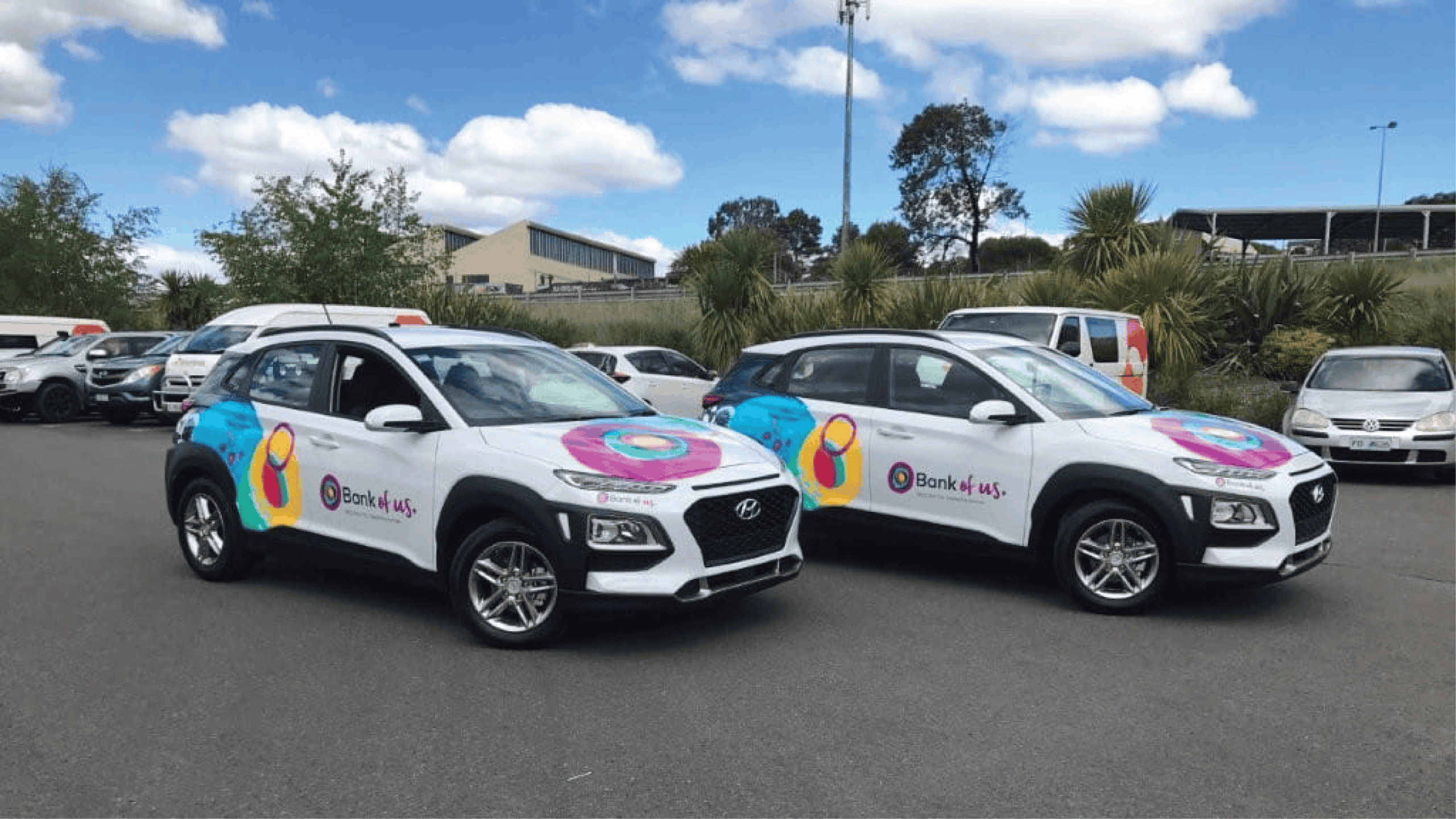Bank of us Fleet Branding Two white Bank of us SUVs with matching colourful vehicle graphics across their bonnets and sides.