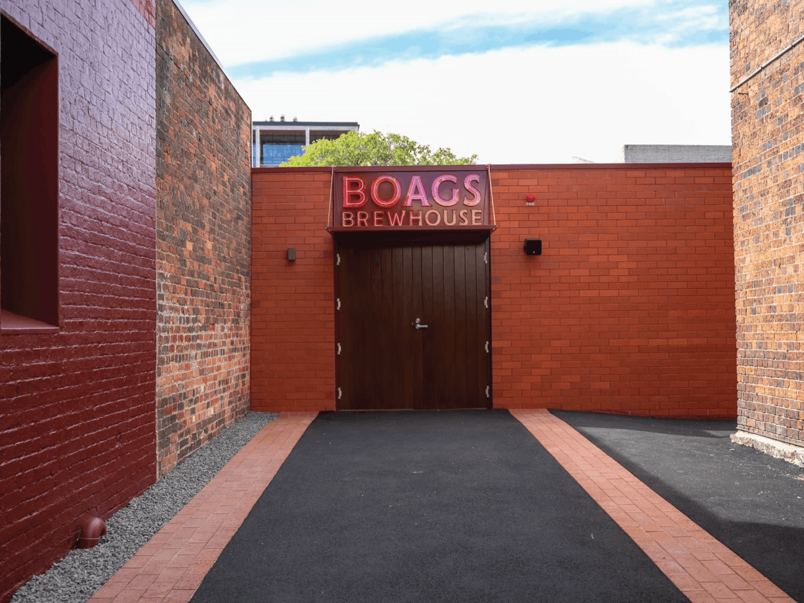 Brick-lined approach to closed timber doors beneath a red Boags Brewhouse entrance sign.