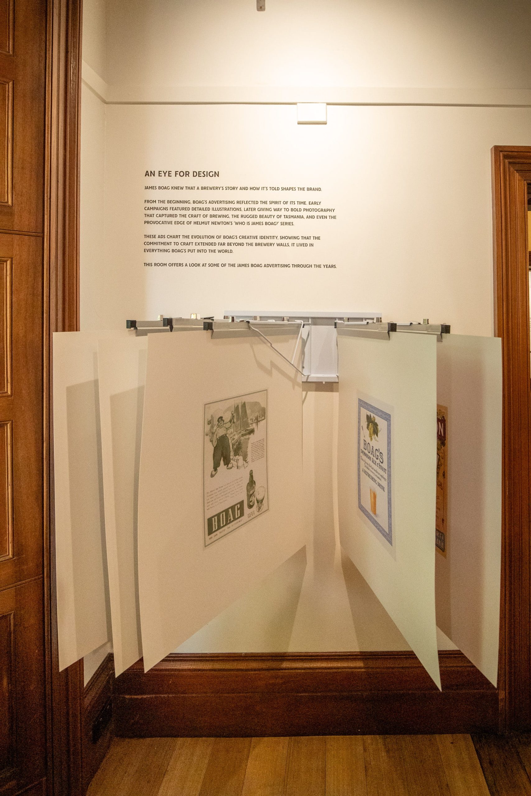 Hinged panels displaying historic Boag’s advertisements beneath wall text headed “An Eye for Design”.